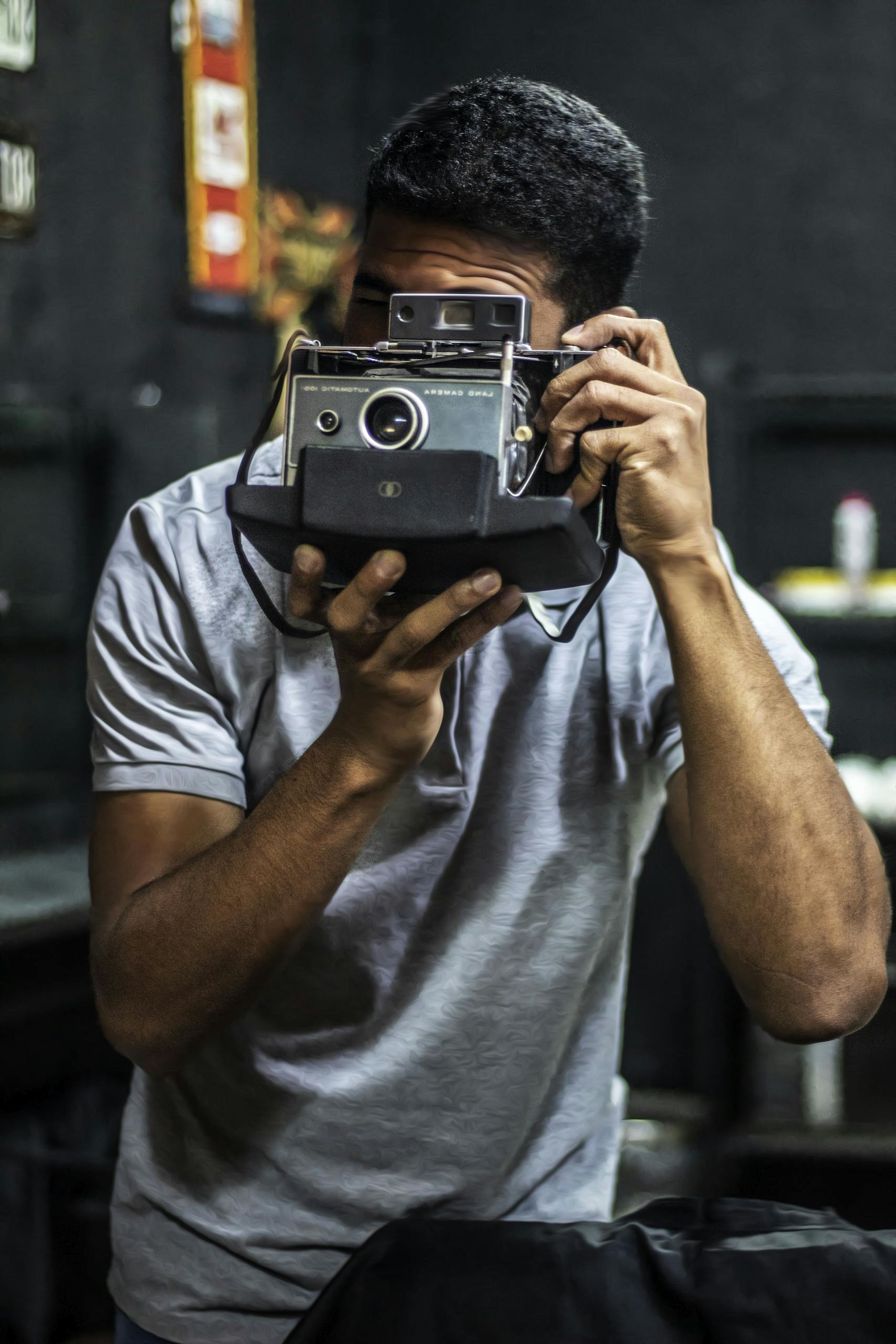 Young adult using a classic vintage camera indoors, focused on photography.